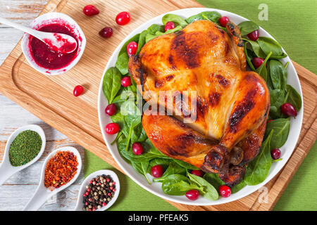 Deliziosa dorate e croccanti tutta la pelle di pollo grigliato servito con rucola, spinaci e insalata a base di mirtillo palustre sulla piastra bianca sul tagliere con salsa di frutti di bosco Foto Stock