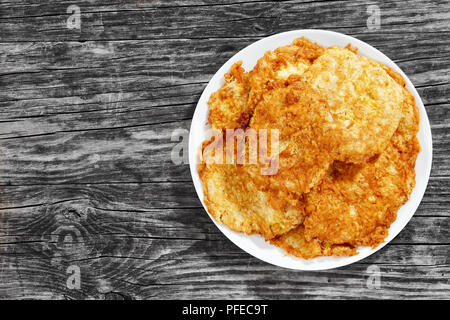 Oven-Fried costolette di maiale sul piatto bianco, sul vecchio legno scuro, sfondo semplice ricetta, vista da sopra Foto Stock