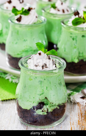 I kiwi Mousse Cheesecake dolce conditi con panna montata e scaglie di cioccolato in bicchieri di vetro sul vecchio tavolo in legno, vista verticale dall'alto, Foto Stock