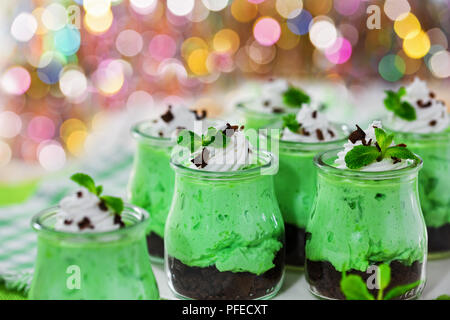 Deliziosa la menta kiwi Spuma di Formaggio la torta con panna montata scaglie di cioccolato e foglie verdi in Dessert le coppe di vetro su sfondo bokeh, selectiv Foto Stock