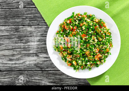 Insalata di prezzemolo o tabulé sul piatto bianco, facile e sana classic piatto vegetariano con bulgur, i pomodori, il prezzemolo, la cipollina e menta, olio d'oliva Foto Stock