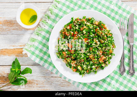 Insalata di prezzemolo o tabulé, medio-orientale piatto vegetariano con bulgur, i pomodori, il prezzemolo, la cipollina e menta, spruzzata con olio di oliva e limone Foto Stock