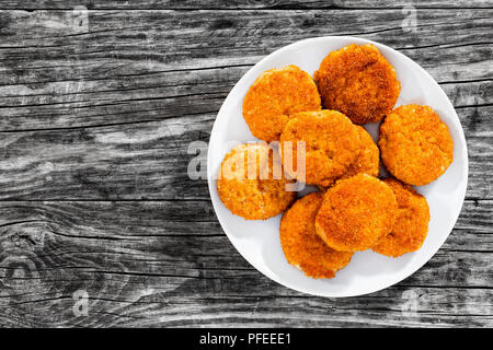 Delizioso fritto costolette di carne sulla piastra bianca sul vecchio dark di tavole di legno, vista da sopra Foto Stock