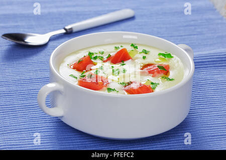 Salmone affumicato e formaggio cremosa zuppa deliziosa purea cosparsa di prezzemolo in zuppa di bianco cup sulla tabella MAT con cucchiaio, vista da sopra, close-up Foto Stock