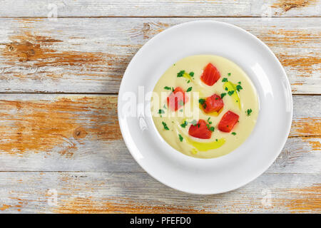 Hot cremosa zuppa piccante purea con salmone affumicato cosparsa di prezzemolo in bianco ampia piastra del cerchione sulla tavola, facile e veloce la ricetta, vista da sopra Foto Stock