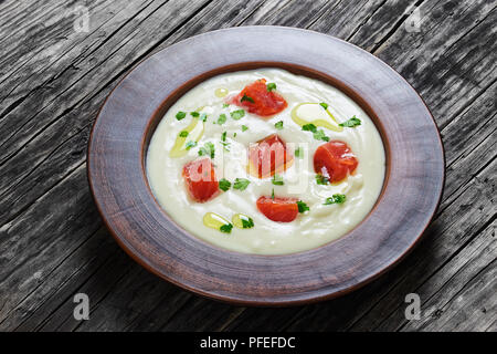 Caldo speziato cremosa zuppa di salmone cosparsa di prezzemolo in bianco ampio cerchio piastra di argilla sul vecchio dark tavolo rustico, vista da sopra, close-up Foto Stock