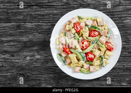 Cetriolo, formaggio, omelette, prosciutto, pomodori, insalata con yogurt, mostarda dressing - leggero e rinfrescante piatto laterale sulla piastra bianca sul vecchio legno scuro Foto Stock