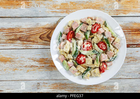 Cetriolo, formaggio, omelette, prosciutto e pomodoro insalata deliziosa cosparsi di pepe macinato fresco e origano essiccato sul piatto da portata dressing di yogurt con la senape s Foto Stock