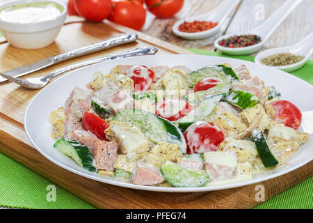 Con insalata di carne, cetriolo, pomodoro, formaggio, omelette e fette di mela con yogurt senape medicazione sulla piastra bianca sul tagliere con posate e s Foto Stock