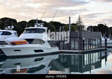 Grandi yacht in marina accanto a floating edificio per uffici su molto calma della superficie dell'acqua. Foto Stock