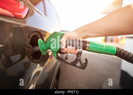 Closeup dell uomo di pompaggio del carburante benzina in auto alla stazione di gas. Gas ugello della pompa nel serbatoio del carburante di una vettura di colore grigio Foto Stock