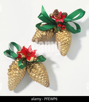 Due coppie di golden pigne decorate con archetti verde e fiori di colore rosso Foto Stock
