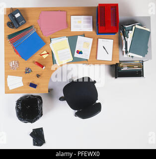 Scrivania da ufficio con documenti cartacei, vassoi, cartelle, strumenti di scrittura, foratura, cucitrice, sedia girevole Filing cabinet e un cestino con scomparto nero camicie, vista da sopra Foto Stock