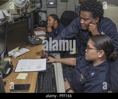 5TH FLOTTA AREA DI OPERAZIONI (5 giugno 2018) specialista della logistica 1a classe Toni, acido da St. Louis, Missouri (in piedi), treni specialista della logistica di seconda classe Lumbang Rheava, dal Guam, nel magazzino ufficio di controllo a bordo del Wasp-classe assalto anfibio nave USS Iwo Jima (LHD 7), 5 giugno 2018. Iwo Jima, homeported a Mayport Fla., è sulla distribuzione per gli Stati Uniti Quinta Flotta area di operazioni a sostegno della sicurezza marittima operazioni per rassicurare gli alleati e partner e preservare la libertà di navigazione e il libero flusso di commercio nella regione. Foto Stock