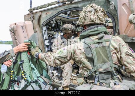 Un esercito britannico soldato assegnato per la 130Deutsch Engineer Battaglione fornisce giubbotti di salvataggio per i soldati delle truppe di Fox, 2° Stormo, 2d della Cavalleria durante una contestazione di wet gap crossing in prossimità di Kaunas, Lituania, 13 giugno 2018. Quasi 200 Strykers e sostegno militare di veicoli sono stati traghettato con successo attraverso il fiume Neman, lanciando la potenza di combattimento in avanti e che si estende 2CR raggiungere operativa. 2CR sta attualmente supportando gli Stati Uniti Esercito Europa-led esercizio multinazionale Saber Strike 18. Foto Stock