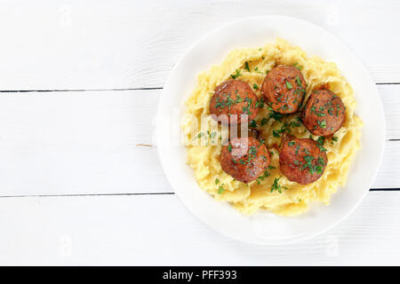 Deliziose polpette di carne servita calda con purea di patate purea sulla piastra bianca sul tavolo di legno, vista da sopra Foto Stock