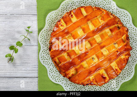 In casa deliziosi dolci di ricotta torta con uvetta, le mandorle e la scorza di arancia sul openwork tovagliolo bianco sul tavolo di legno con la menta, vista da sopra Foto Stock