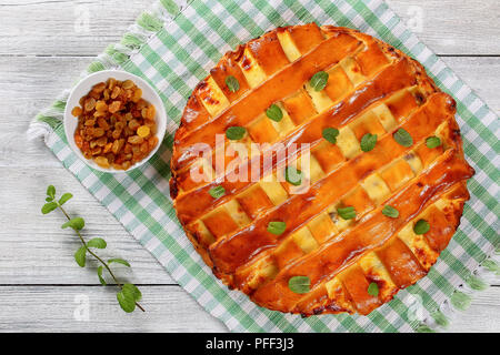 In casa deliziosi dolci di ricotta torta con uvetta, le mandorle e la scorza di arancia sul tovagliolo bianco sul tavolo di legno con la menta, vista da sopra Foto Stock