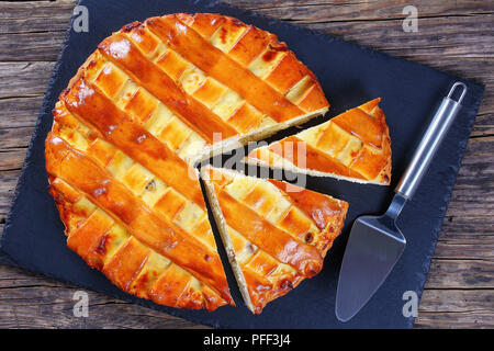 In casa deliziosi dolci di ricotta uvetta, mandorle, torta alla vaniglia con tagliare fette su nero ardesia vassoio con pala torta, vista da sopra Foto Stock