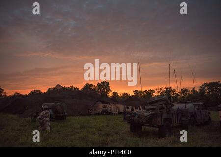 Un esercito di Oklahoma soldato della protezione nazionale assegnato al quarantacinquesimo campo brigata di artiglieria (FAB) cammina verso il quarantacinquesimo FAB mobile Tactical Operations Center mentre il sole tramonta durante Warfighter 18-5 (WFX) al Camp Atterbury manovra comune centro di formazione nei pressi di Edimburgo, Indiana, 12 giugno 2018. WFX 18-5 è a 9 giorno, 24 ore, continua il comando e controllo esercitazione congiunta condotta al treno e prova le forze dell esercito mediante simulazione al calcolatore, focalizzata sulla 34th divisione di fanteria, Minnesota Guardia Nazionale, la sua formazione primaria pubblico. Foto Stock