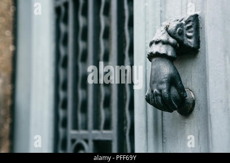 Close-up. Maniglia Vintage per bussare alla porta la forma di una mano. Ingresso al palazzo di appartamenti. Foto Stock