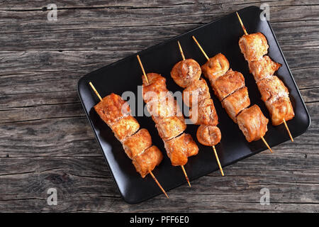 Delizioso pollo shish kebab su spiedini di bambù su nero piatto rettangolare in legno scuro, tabella, vista da sopra Foto Stock