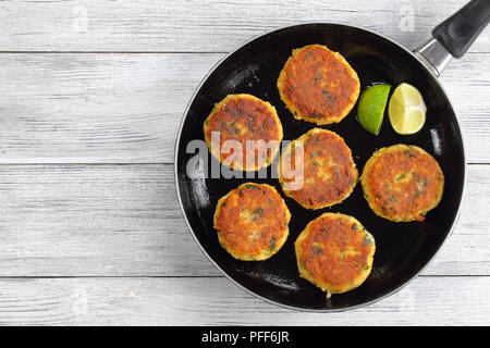 Freschi e deliziosi pesce fritto torte in padella con fettine di lime, autentica ricetta, vista da sopra Foto Stock