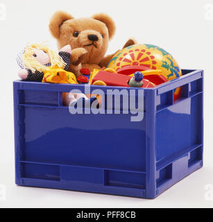 Blue box di plastica riempito di giocattoli compresi ragazza burattino, Teddy bear, la sfera e il giocattolo auto con autista Foto Stock