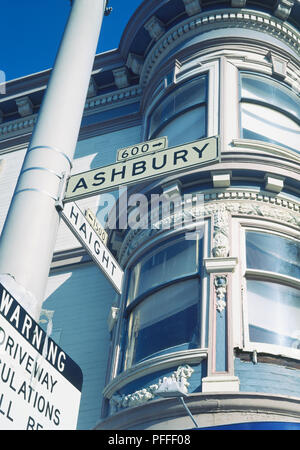 Stati Uniti, California, San Francisco, Haight ashbury street che mostra segni di intersezione di Haight Ashbury e, edificio arrotondato con finestre a baia dietro, vista dal basso. Foto Stock