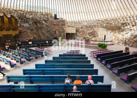 Chiesa Temppeliaukio, vista dentro la Temppeliaukion Kirkko o 'Rock Chiesa' nel centro di Helsinki che mostra i turisti seduti nei suoi banchi blu, Finlandia. Foto Stock