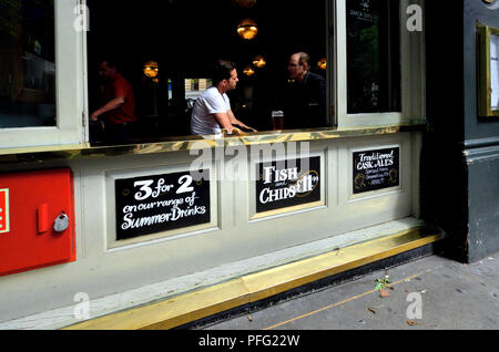 La gente alla finestra aperta del Garrick Arms pub in Charing Cross Road, Londra, Inghilterra, Regno Unito. Foto Stock