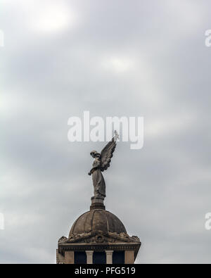 Angelo scultura e una gazza contro il cielo nuvoloso Poblenou cimitero. Foto Stock