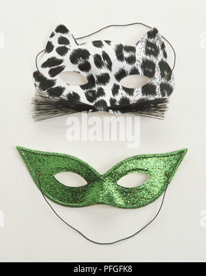Due maschere viso uno nero e bianco macchiato e un verde glitter maschera. Foto Stock