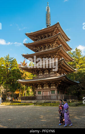 Un paio di donne giapponesi che indossano kimono tradizionali cammina davanti a un tempio nella città di Kyoto, Giappone. Foto Stock