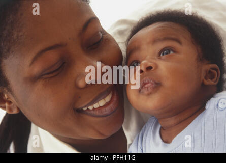 Donna giacente sul suo lato di fianco al baby sitting fino, guancia a guancia, close-up. Foto Stock