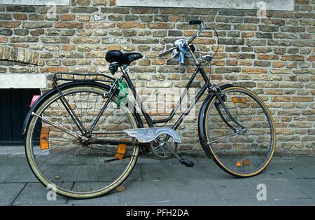 Bicicletta appoggiata contro un muro di mattoni Foto Stock