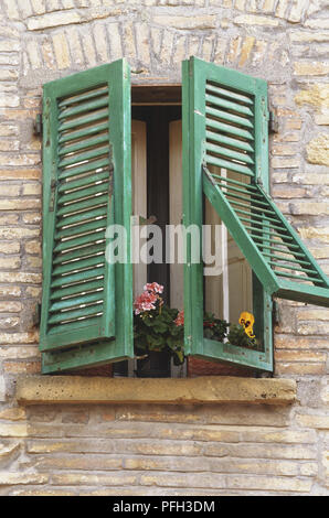 L'Italia, parte occidentale della Toscana, Volterra, finestra con aperto a metà, persiane di legno verde e i fiori sul davanzale Foto Stock