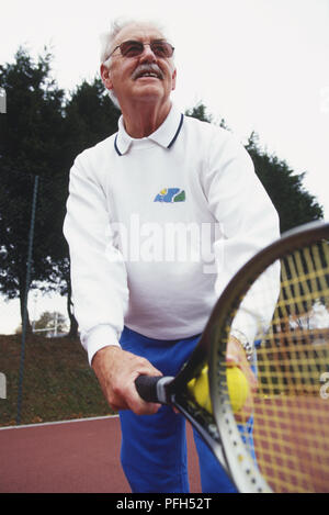 Uomo maturo giocando a tennis circa per servire. Foto Stock