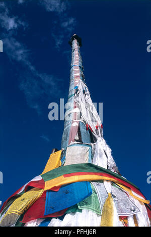 Cina, Tibet, Lhasa, Barkhor, Jokhang Tempio, polo verticale avvolte in colorati bandiere di preghiera e a basso angolo di visione. Foto Stock