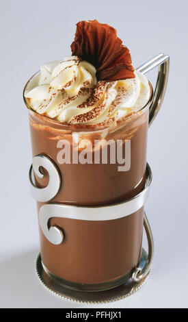 Cioccolata calda la torta con panna montata e riccioli di cioccolato decorate in vetro, vicino. Foto Stock