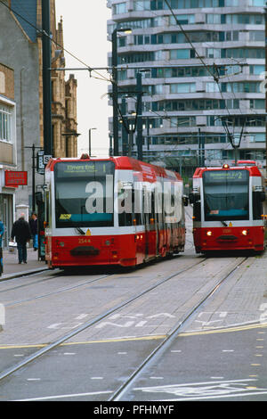 Due red tram viaggiano affiancati in strada, vista frontale. Foto Stock