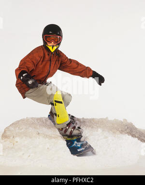 Ragazzo in casco, occhiali e ginocchiere snowboard sulla neve pendenza,  vista frontale Foto stock - Alamy