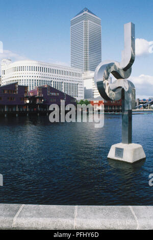 England, London, riverside view of Canary Wharf with modern sculpture on the water in the foreground, low angle view. Foto Stock