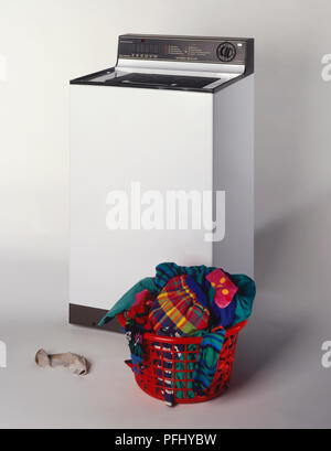 Parte superiore del caricatore della macchina di lavaggio, rosso cesto in plastica riempito con lavaggio, vista frontale. Foto Stock