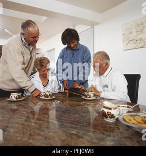 Due coppie alla ricerca attraverso un album di foto Foto Stock