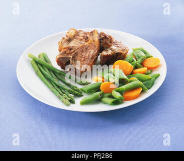 Due costolette di agnello grigliate sul piatto con gli asparagi, i baccelli, e carote Foto Stock