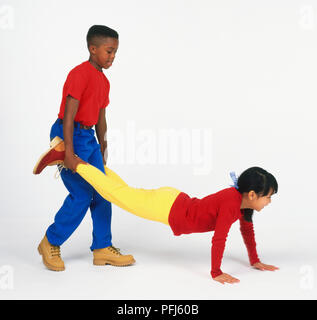 Ragazzo e una ragazza in abiti colorati giocando "carriola' Foto Stock