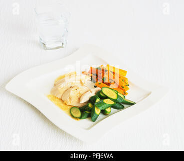 Fette di pollo, pezzi di zucchina e tagliato in julienne carote servita sulla piastra squadrata. Foto Stock