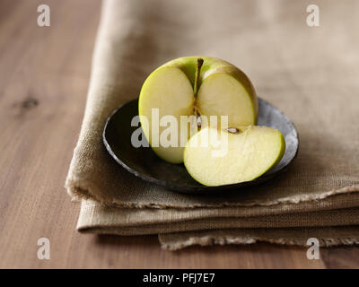 Apple tagliate a metà in una terrina appoggiata su tela Foto Stock