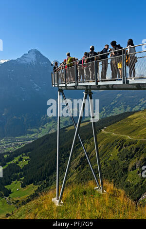 I turisti alla piattaforma di avvistamento alta sopra Grindelwald nella valle, Eiger northface dietro, prima scogliera a piedi da Tissot, Grindelwald, Svizzera Foto Stock